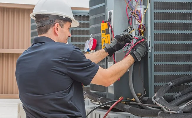 HVAC technician checking electrical connections on cooling equipment