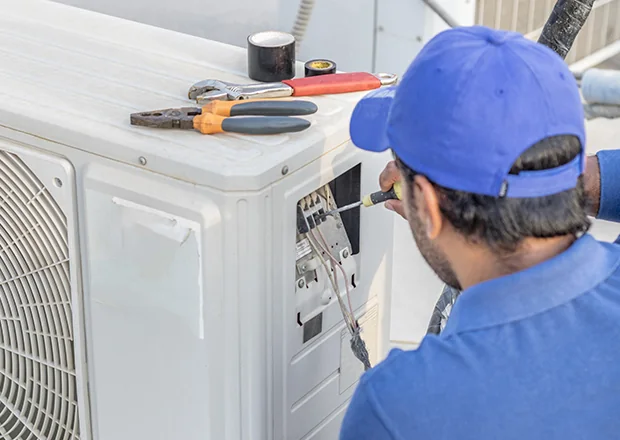 Technician inspecting the control panel of an outdoor HVAC system